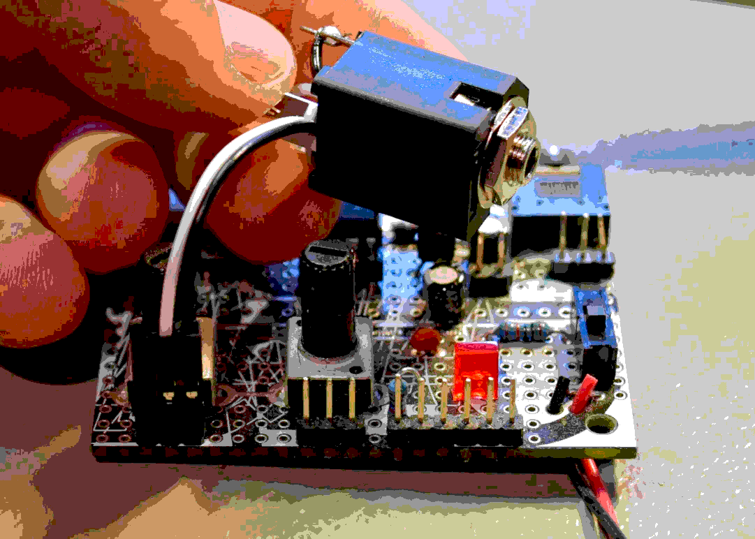 Close-up of a hand holding an adapter, a jack is connected via two wires to a small pcb.